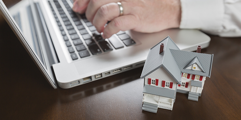 Miniature House Near Male Hands Typing on Laptop Computer | commercial property management software
